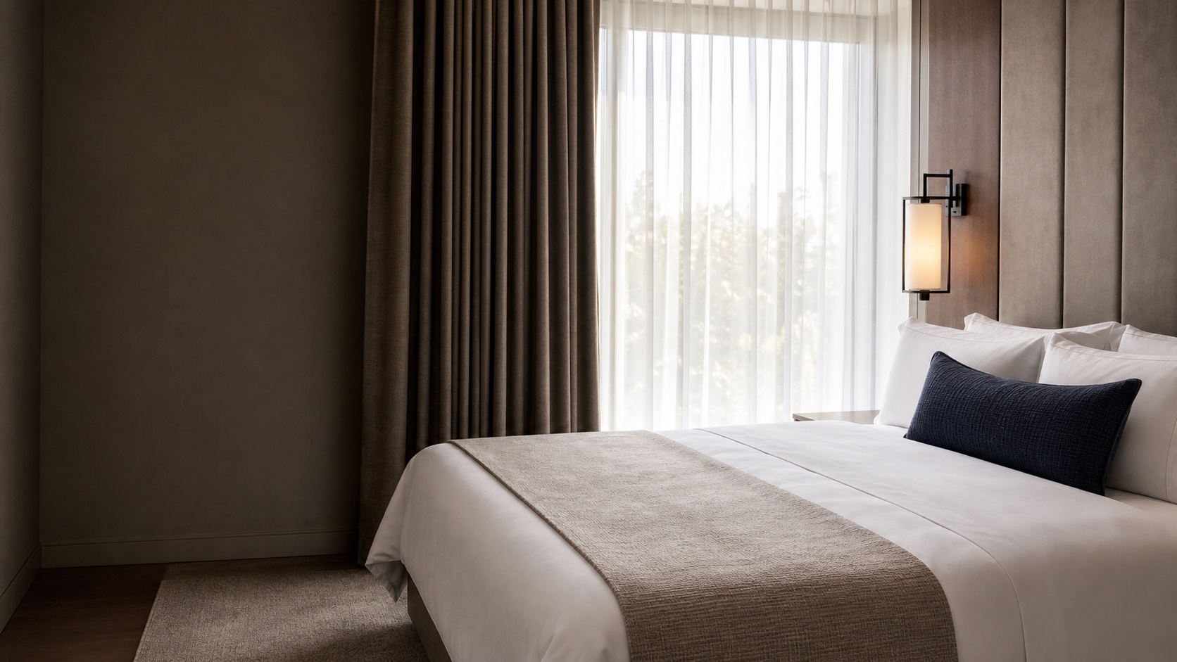 A refined hotel guest room with coordinated bedding and window textiles